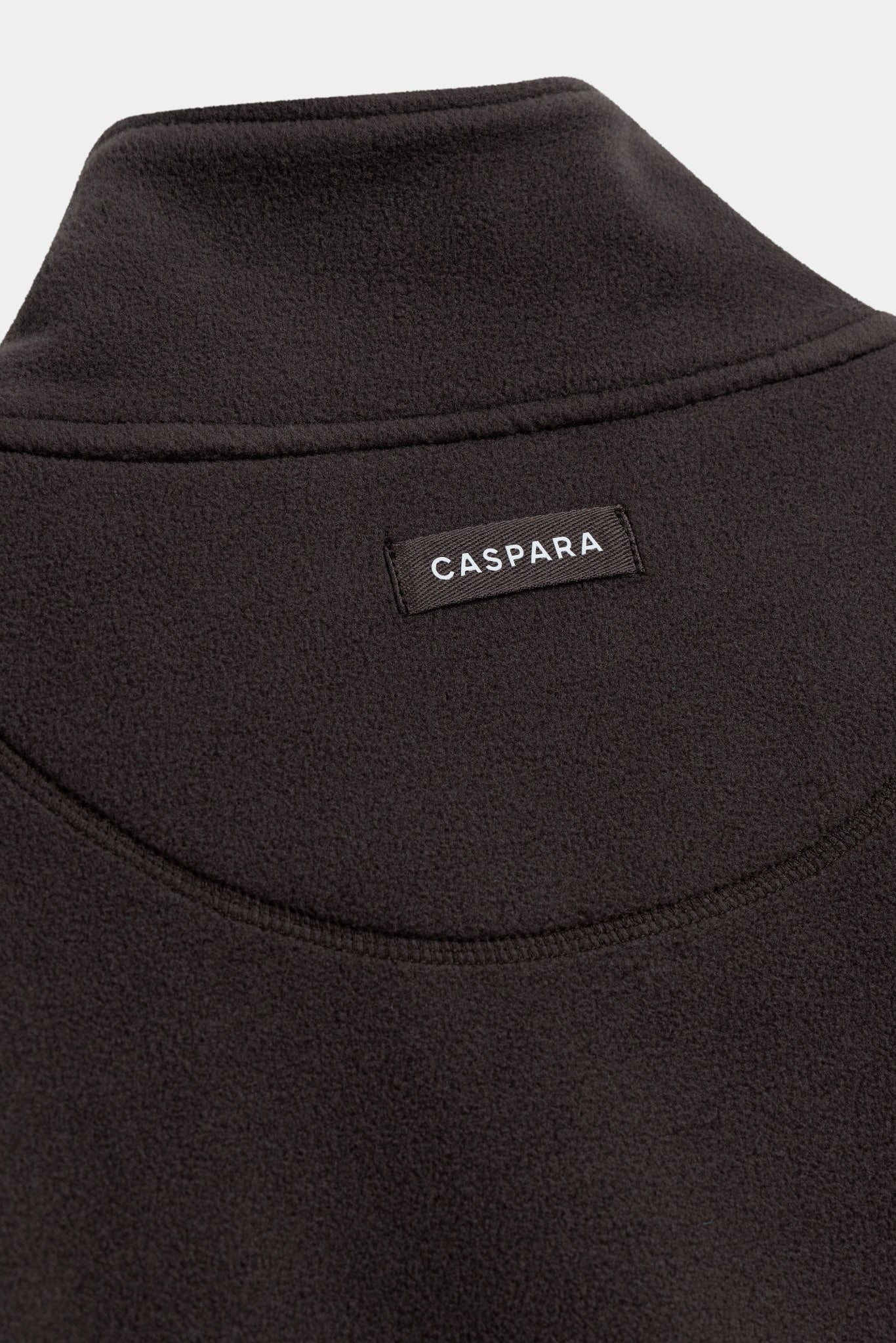 Close-up of the back neck and CASPARA logo label on an espresso brown polar fleece pullover.