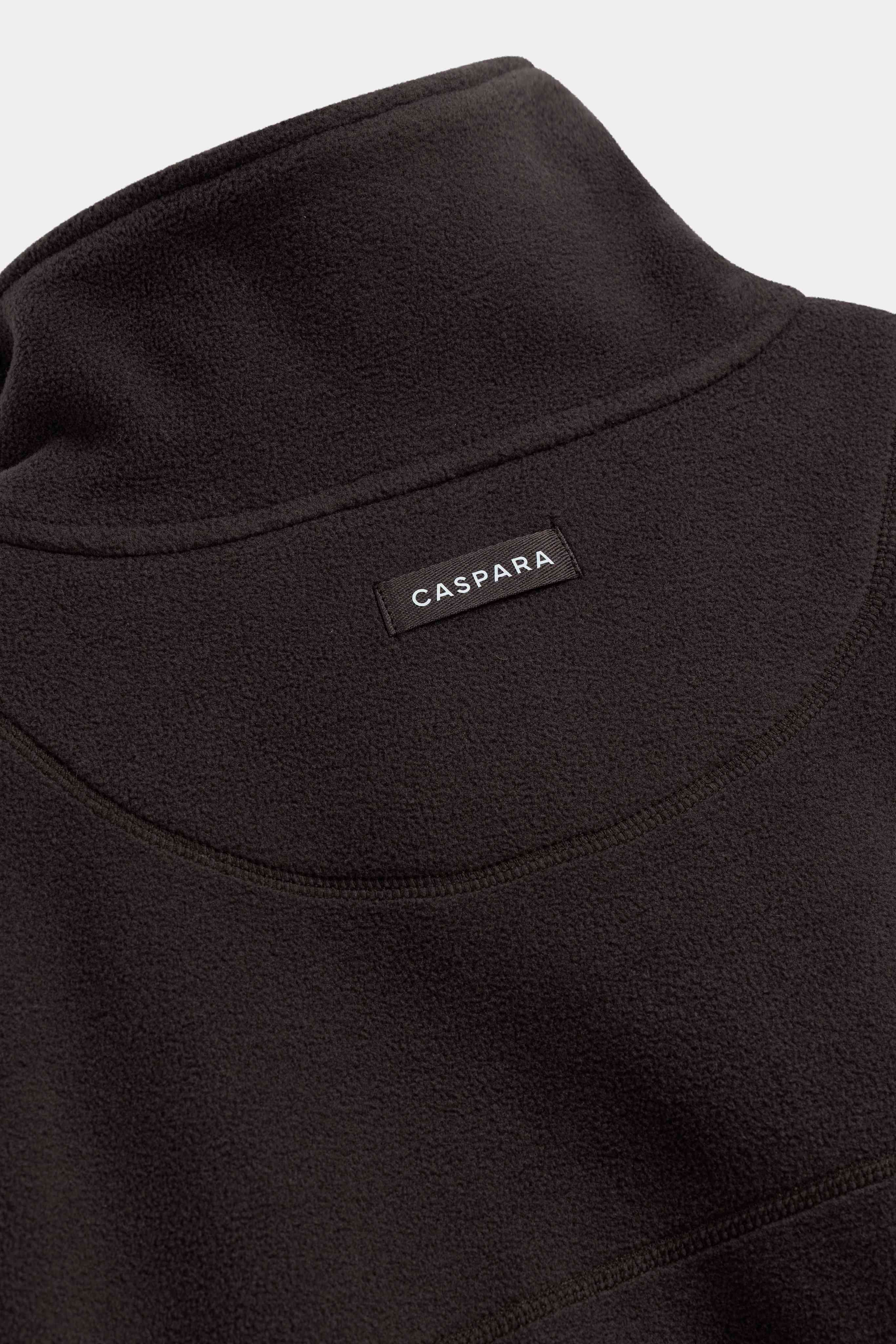 Close-up of the CASPARA logo label on the back of an espresso polar fleece pullover.