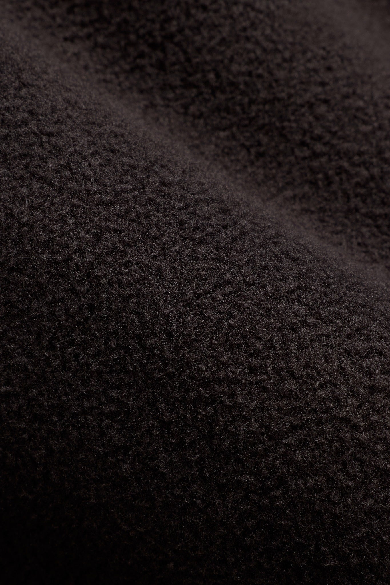 Close-up of textured cocoa bean brown polar fleece fabric on a CASPARA pullover.