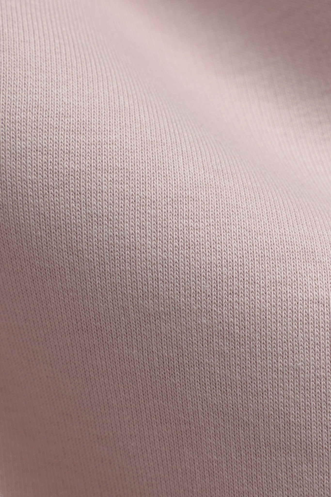 Close-up of dusty pink cotton-blend fabric texture on a CASPARA hoodie.