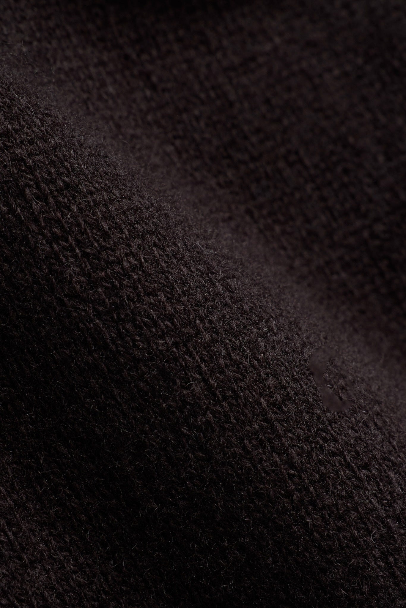 Close-up of dark cocoa bean brown wool knit fabric on CASPARA pants.