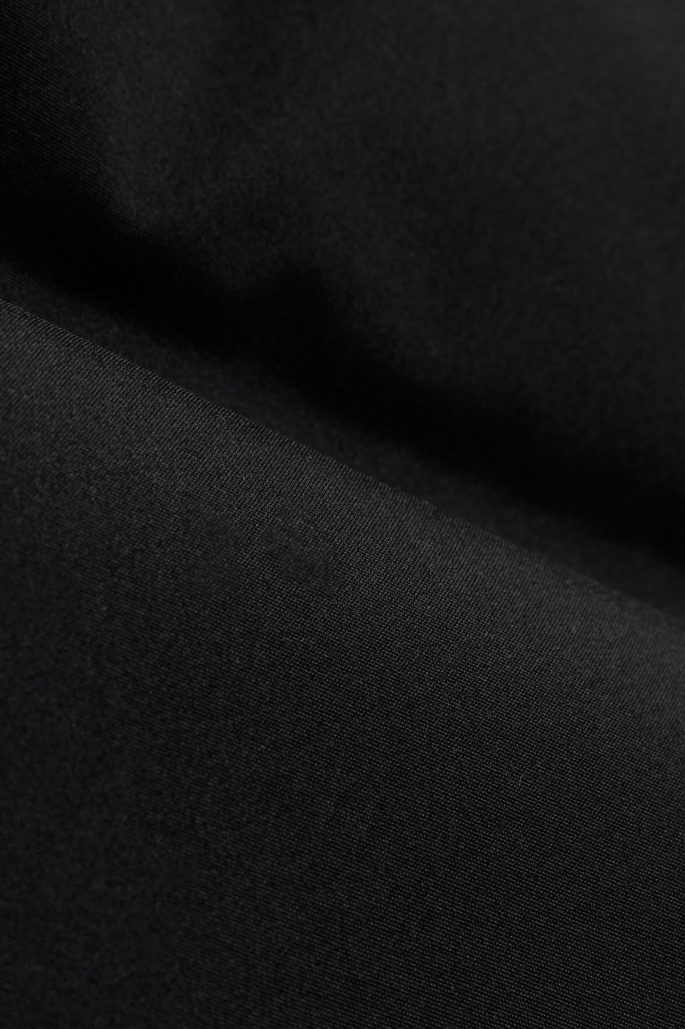 Close-up of the black polyester fabric texture on the CASPARA Boreal Puffer Vest.
