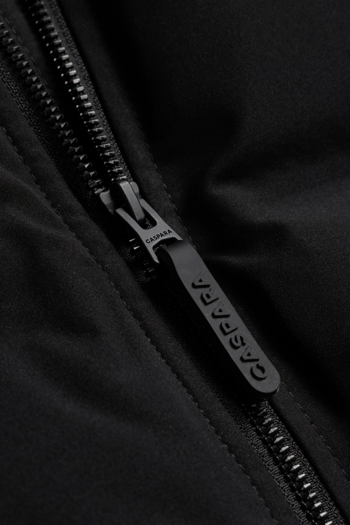Close-up of the black zipper and embossed CASPARA logo pull on the Boreal puffer vest.