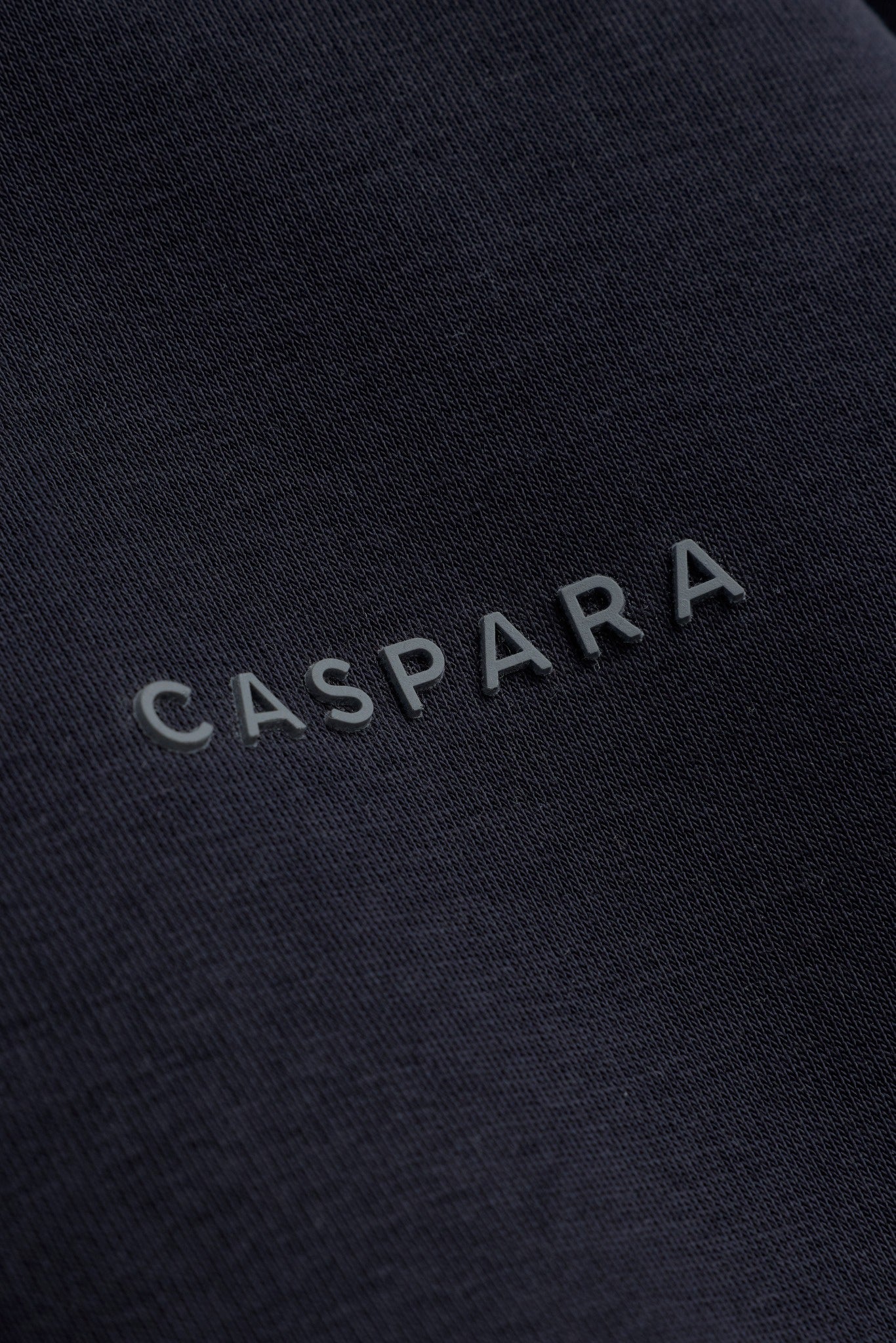 Close-up detail of the raised CASPARA logo on a mineral black sweatshirt.