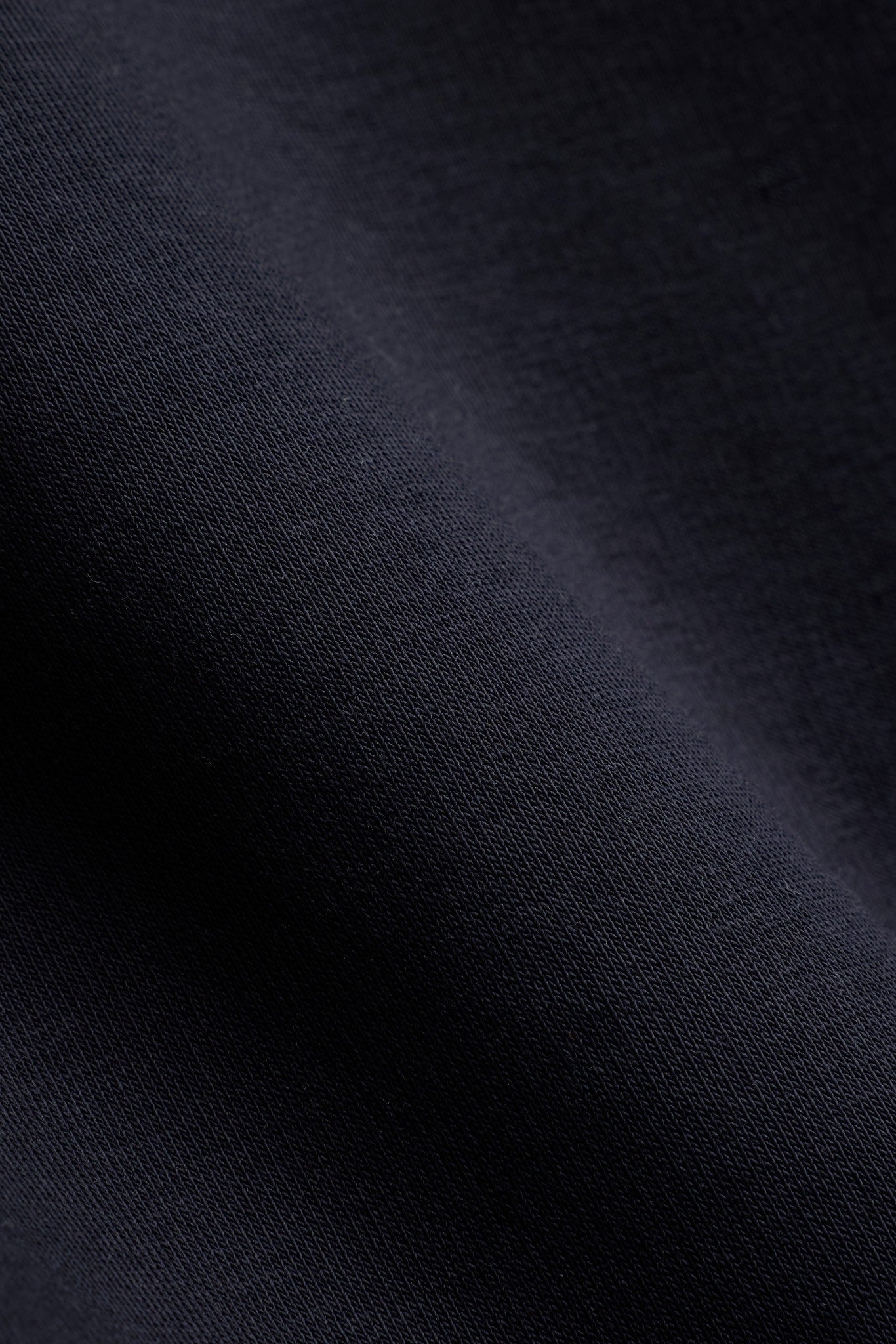 Close-up detail of folded mineral black cotton fabric on a CASPARA sweatshirt.