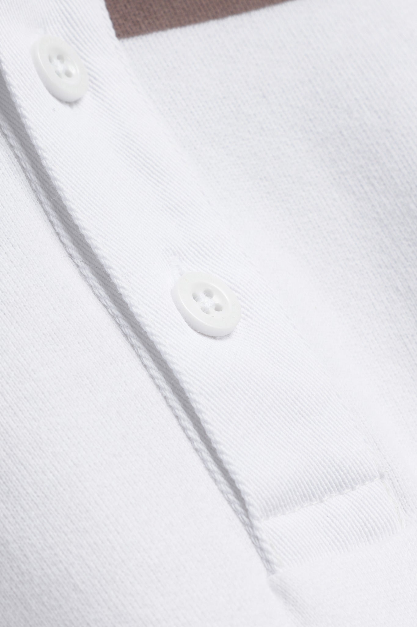 Close-up of the white button placket on a CASPARA walnut and white striped rugby shirt.