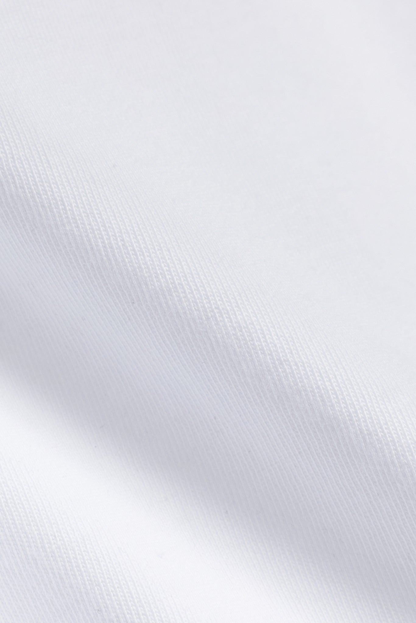 Close-up of the white heavyweight cotton fabric texture on a CASPARA t-shirt.
