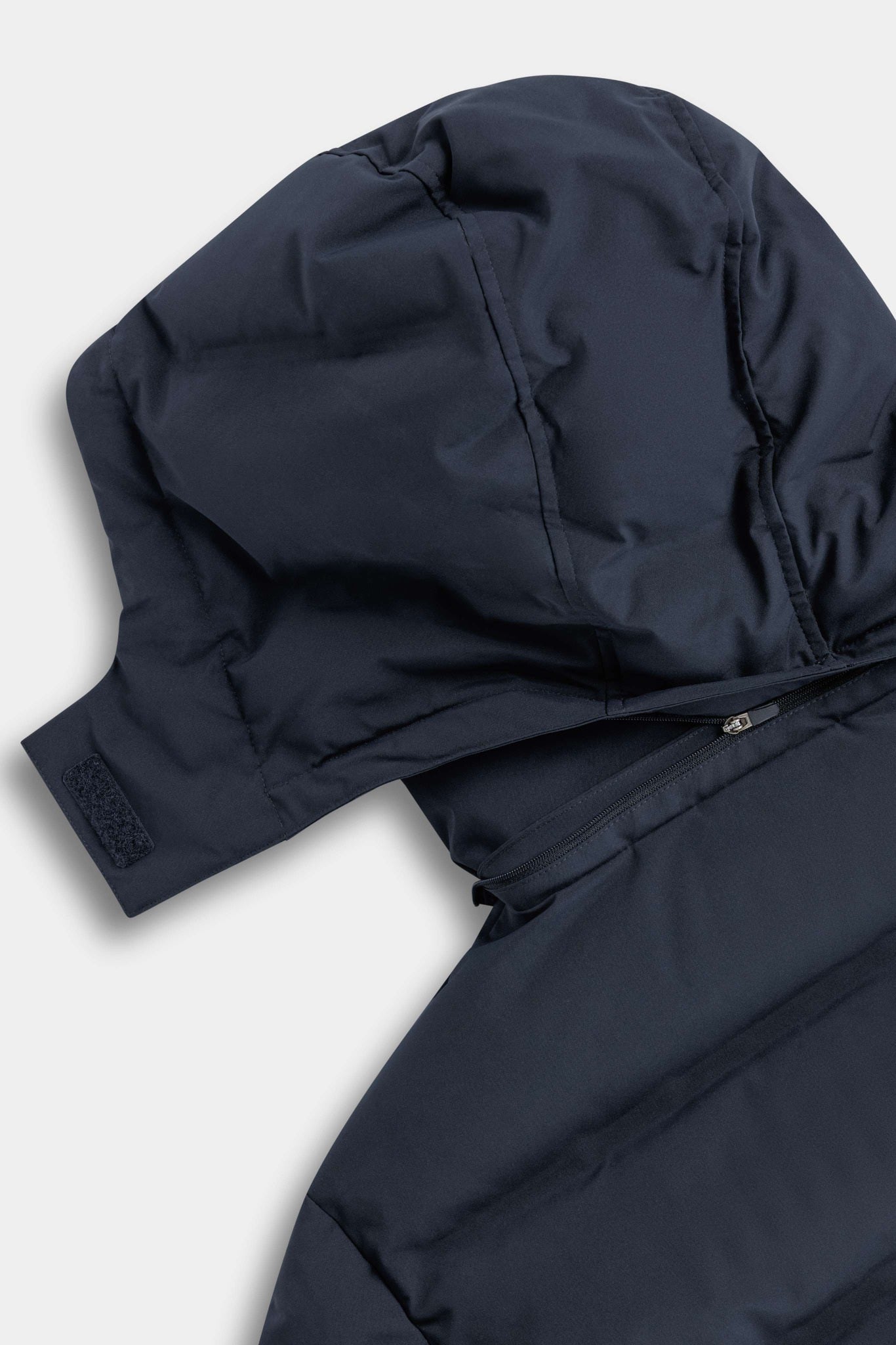 Close-up of the removable hood zipper on the navy CASPARA Aurora puffer jacket.