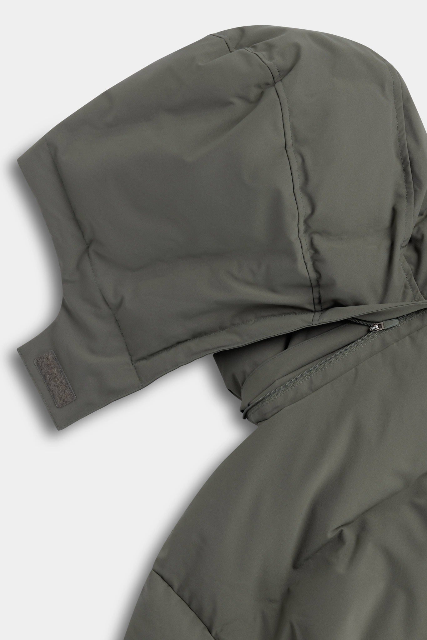 Close-up of the removable hood zipper detail on the khaki CASPARA Aurora puffer jacket.