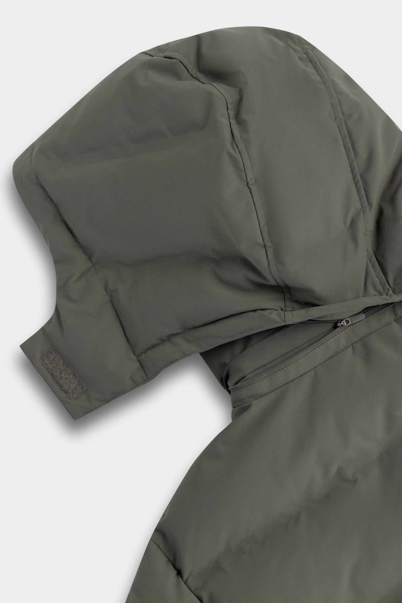 Detachable hood zippered onto the collar of a khaki CASPARA Boreal puffer jacket.